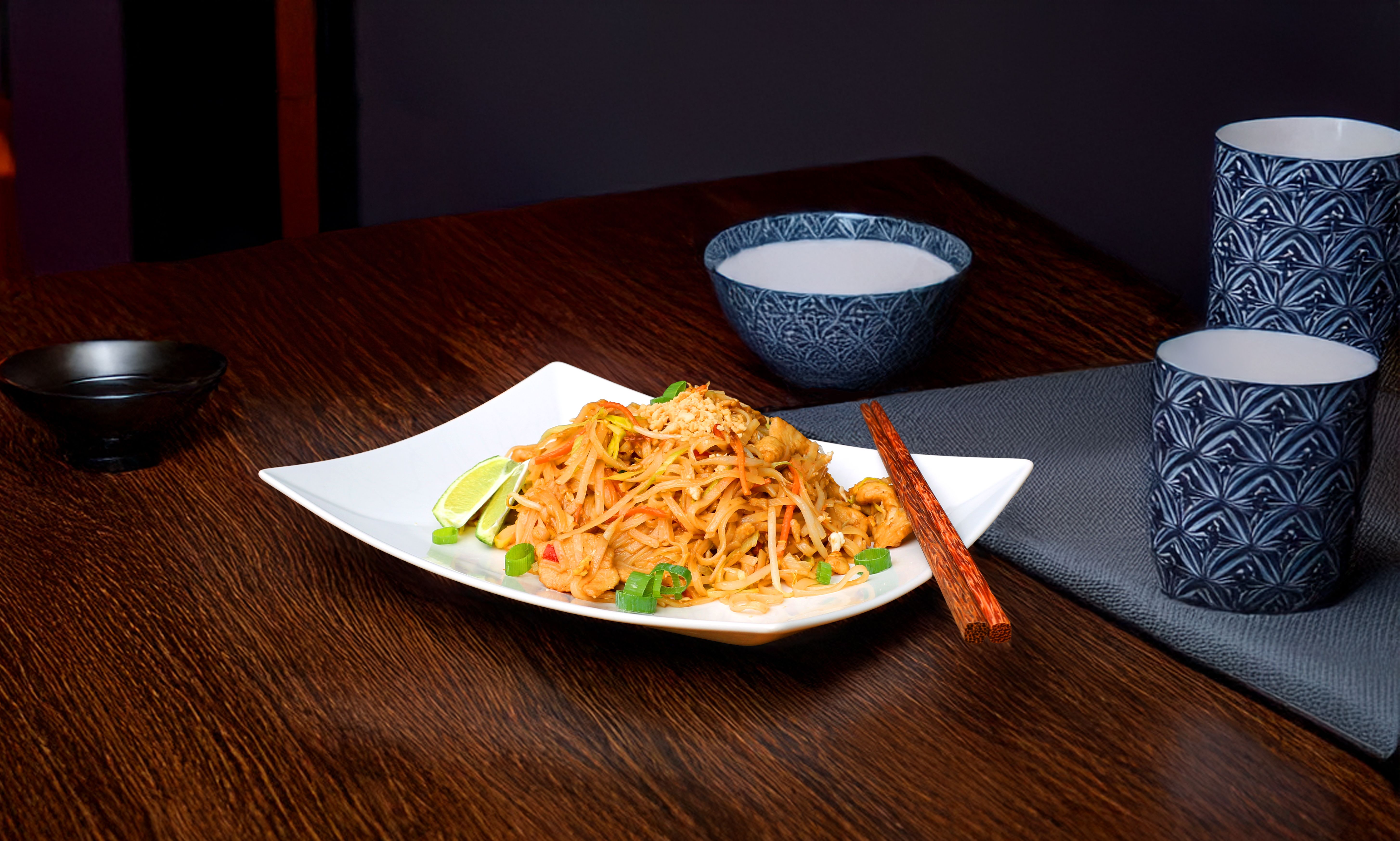 En tallrik Pad Thai står på ett bord.