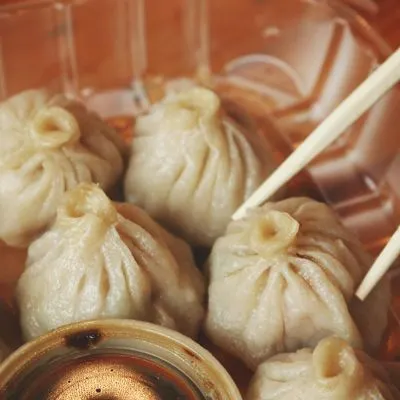 En ångkokt dumpling plockas upp med pinnar.